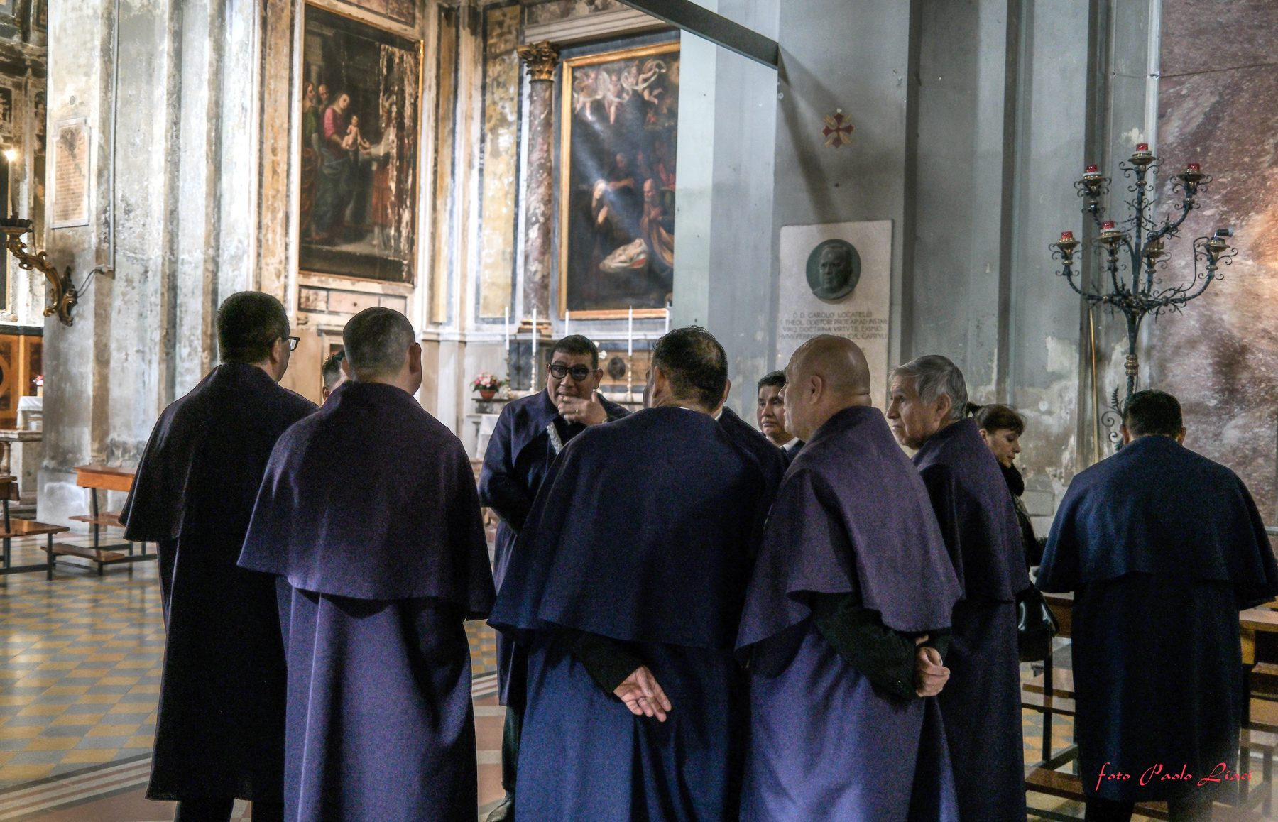 Hermanos in abito viola raccolti in preghiera all'interno della chiesa